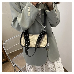 Détail du sac croissant tissé avec bandoulière à rivets sur mannequin en blazer