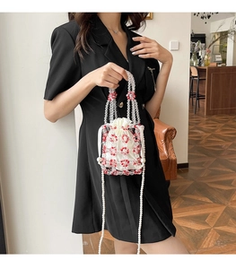 Detail of red floral beaded bucket bag with drawstring liner and pearl shoulder strap