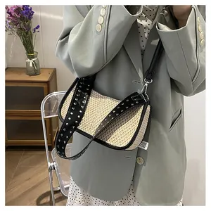Détail du sac bandoulière en paille tressée beige avec bordure cuir noir et rivets
