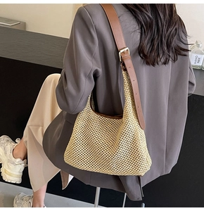 Detailed close-up of straw woven shoulder bag with adjustable brown leather strap