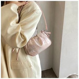 Detail of light pink floral jacquard pattern and silver chain strap on the shoulder bag