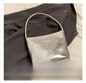 Détail du sac argenté métallisé montrant le cuir froissé brillant et le logo embossé