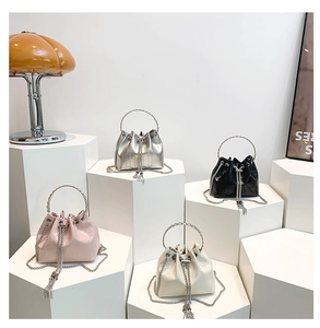Close-up of five crocodile pattern drawstring bucket bags with chain tassels and metal handles