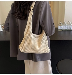 Detailed view of woven straw shoulder bag featuring mesh cut-outs and leather strap