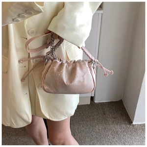 Detail view of pink floral jacquard crossbody bag with drawstring and silver chain strap