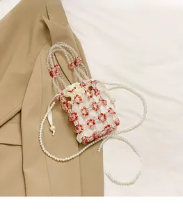 Detail of red floral beaded bucket bag with white drawstring liner and pearl strap