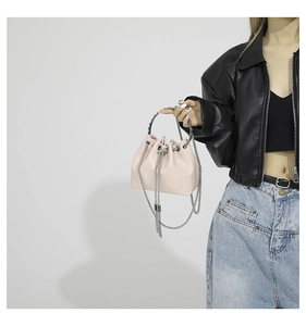 Detail of light pink crocodile pattern bucket bag with silver ring handle and chains