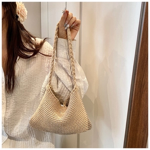 Detail of hand-woven beige knit tote bag with thick strap in minimalist indoor setting