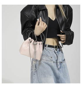 Detail of light pink bucket bag with textured leather, silver ring handle and chain straps