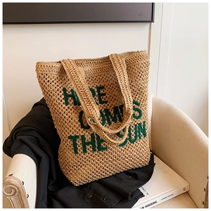 Straw woven tote bag with green embroidered Here Comes The Sun text and twin shoulder straps
