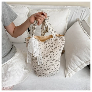 Détail d'un sac à main en toile fleurie avec nœud en dentelle et décor chaleureux