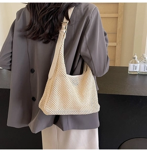 Detail view of woven mesh shoulder bag with cream leather strap and gold buckle adjustment