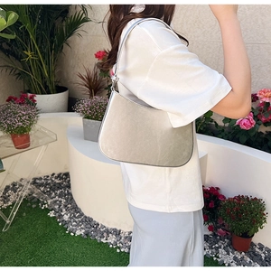Silver metallic hobo bag worn by a model in a garden, minimalist underarm style