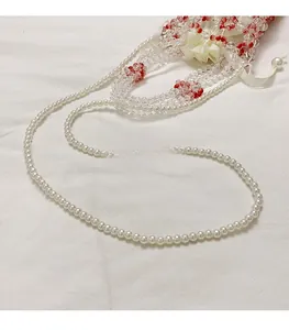 Detail of beaded shoulder strap with white pearls, red beads, and silk flower accessory