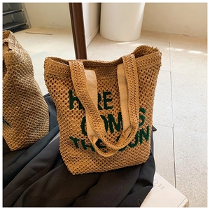 Handmade straw tote bag with green embroidered Here Comes The Sun text and wide handles
