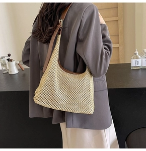 Detail of hand-woven straw tote with premium brown leather trim and golden metal buckle