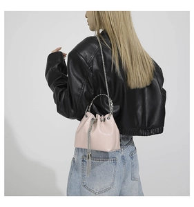 Detail of pink faux leather bucket bag with silver chain handle on a female model