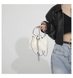 Detail of white PU bucket bag featuring crocodile pattern, metal handle and chain straps