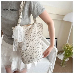 Détail du sac cabas en toile fleurie avec nœud en dentelle dans un décor intérieur