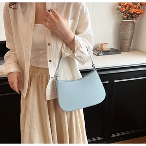 Detail of minimalist light blue hobo bag worn by model in an elegant lifestyle setting