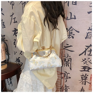 Détail du sac bandoulière en soie avec broderie papillon et poignée dorée sur modèle