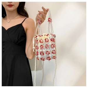 Detail of beaded handbag featuring floral acrylic patterns and a pearl crossbody chain