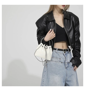 Close-up of white PU leather bucket bag featuring silver chain handles and tassel details