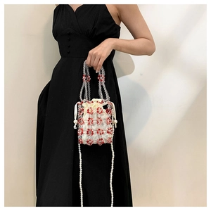 Detail of handmade beaded bucket bag featuring colorful floral patterns and pearl strap