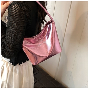 Détail du sac sous le bras rose métallisé montrant la texture brillante et le gaufrage