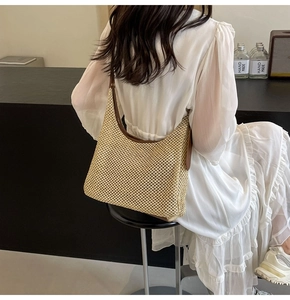 Dettaglio borsa a tracolla in paglia beige con cinturino in pelle e trama a rete fitta