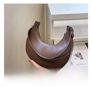 Side view of a brown leather crescent moon shoulder bag with smooth saddle silhouette