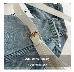 Detail of adjustable golden metal buckle on white crocodile pattern leather shoulder strap