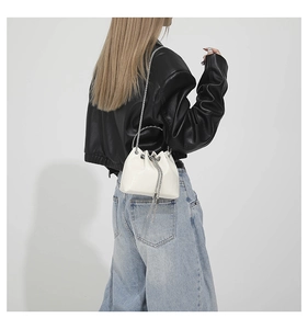 Detailed view of white PU leather bucket bag with silver chain strap and drawstring closure