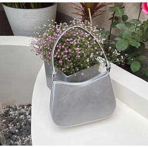 Detailed close-up of a silver crescent handbag with an elegant knotted strap design
