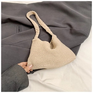 Beige knitted shoulder bag in hobo style placed on a grey blazer for fashion display