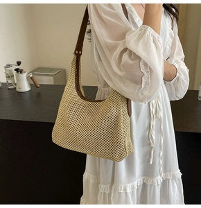 Primo piano della borsa a tracolla in paglia beige con cinturino in pelle marrone