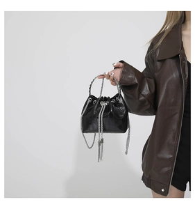 Detail of glossy black bucket bag with silver chain drawstring and fringe tassels