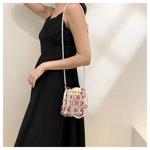 Detail of beaded bucket bag with red floral pattern and white pearl strap