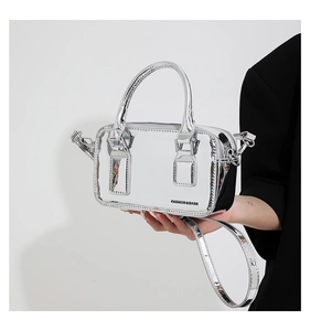 Detail shot of a silver mirror-finish mini crossbody bag with fashion print text