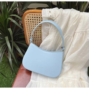 Detail view of light blue half-moon shoulder bag placed on a vintage wooden chair