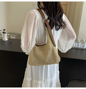 Dettaglio della borsa hobo in paglia intrecciata con tracolla in cuoio marrone