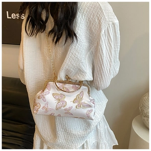 Détail du sac bandoulière en soie avec broderie papillon rose et poignée en métal doré