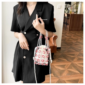 Red and clear beaded bucket bag with floral pattern and pearl shoulder strap on model