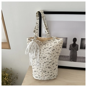 Sac fourre-tout fleuri blanc cassé avec nœud en dentelle sur table en bois rustique