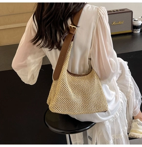 Detailed texture of hand-woven straw crossbody bag with adjustable brown leather strap