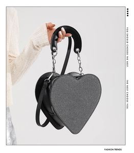 Détail d'un sac à bandoulière en forme de cœur avec paillettes argentées et cuir noir
