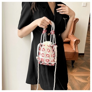 Detail of red floral beaded handbag with satin drawstring pouch and pearl chain strap