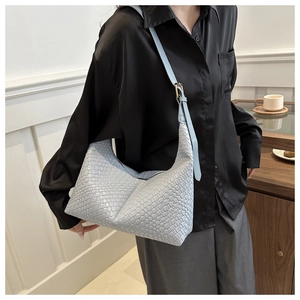 Close-up of a light blue woven leather hobo bag with adjustable strap on a model