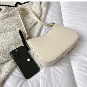 Size comparison between a cream half-moon shoulder bag and a black smartphone