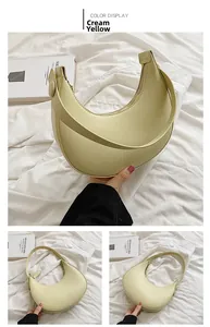 Detail view of a creamy yellow half-moon underarm bag with smooth texture and metal zipper